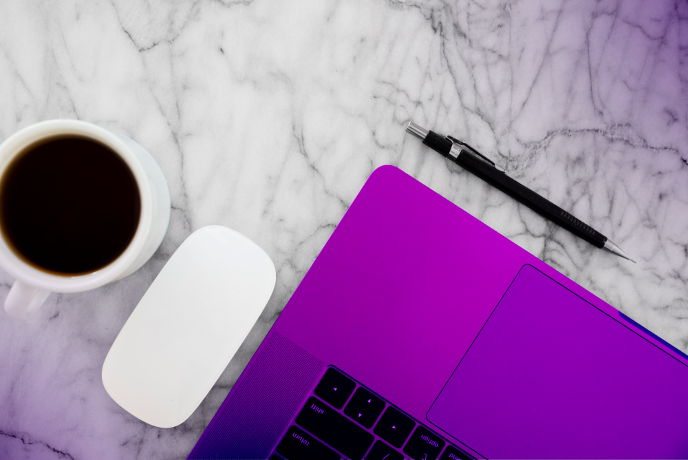 From above, a laptop sits atop a marble table, accompanied by a mousepad, a pen, and a cup of coffee. The setup hints the user is likely researching "Google Local Service Ads for Construction" while enjoying coffee.