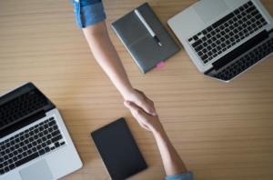 Duas pessoas apertando as mãos, fechando um contrato de consultoria em vendas.