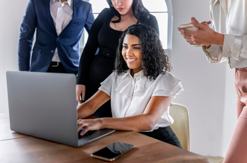 Grupo de vendedores contratados por terceirização comercial vendo os resultados na tela de um notebook.