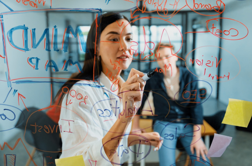 Mulher desenhando um mapa mental em uma lousa, representando a estrutura de um funil de growth.