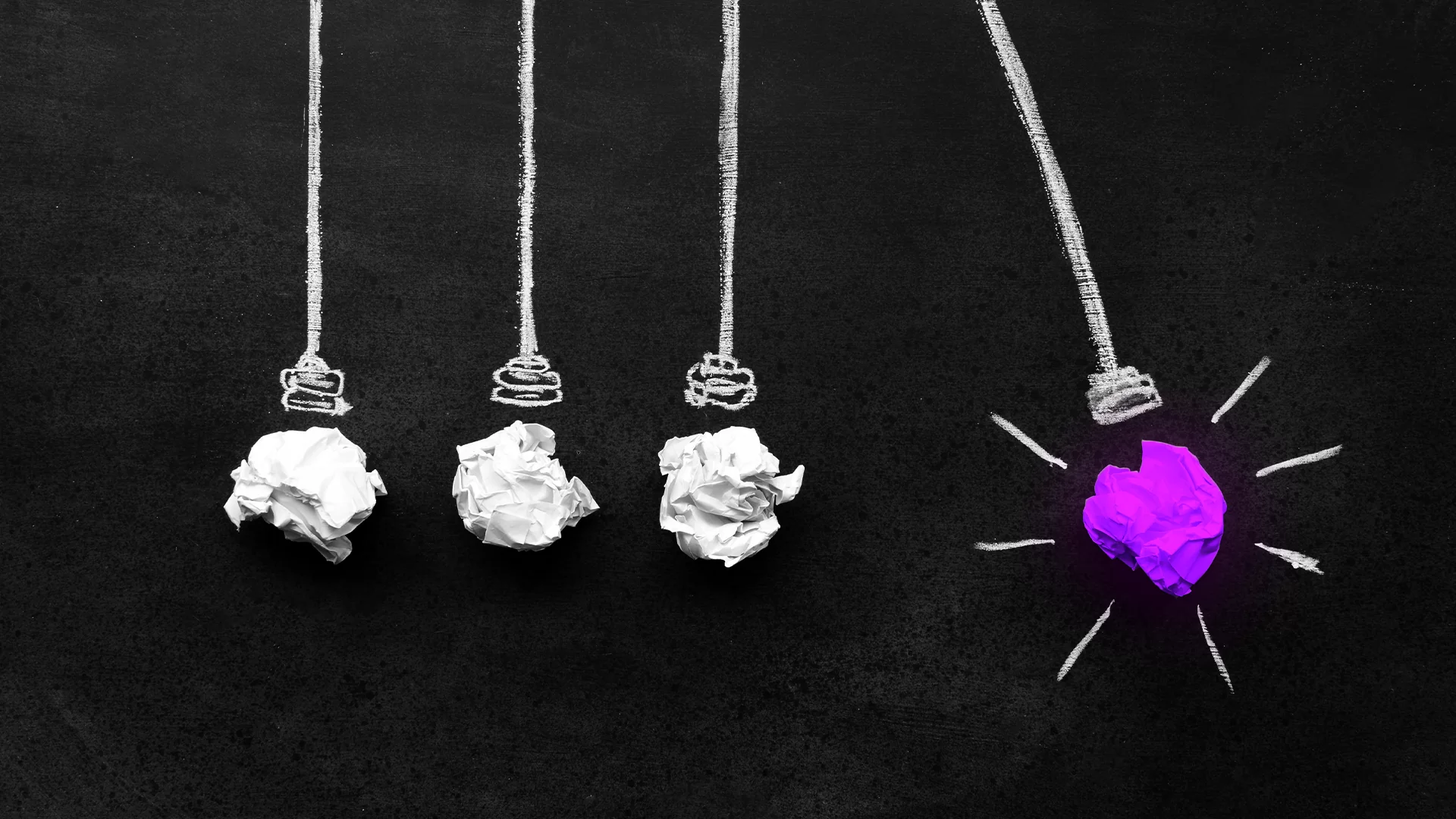 Papéis amassados em branco representando lâmpadas apagadas, e um papel amassado cor de rosa representando uma lâmpada acesa, como uma analogia da diferença de uma empresa de marketing digital para agências convencionais.