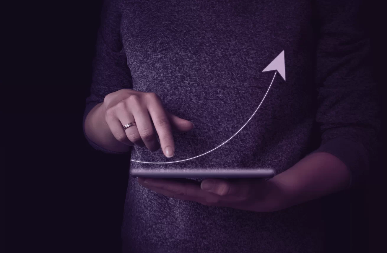 Mão de um homem segurando o tablet com uma seta para cima, representando os retornos do investimento no exterior caso a empresa não cometa os erros citados.