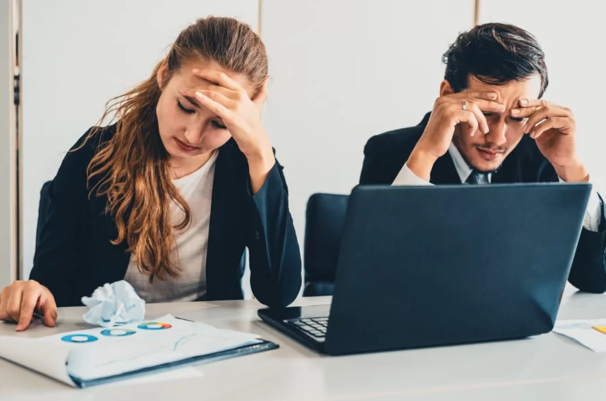 Dois empresários, homem e mulher, estressados pensando em contratar uma equipe de vendas terceirizada
